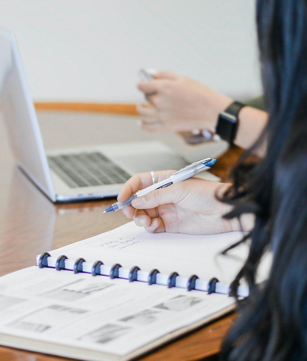 person holding pen writing on paper